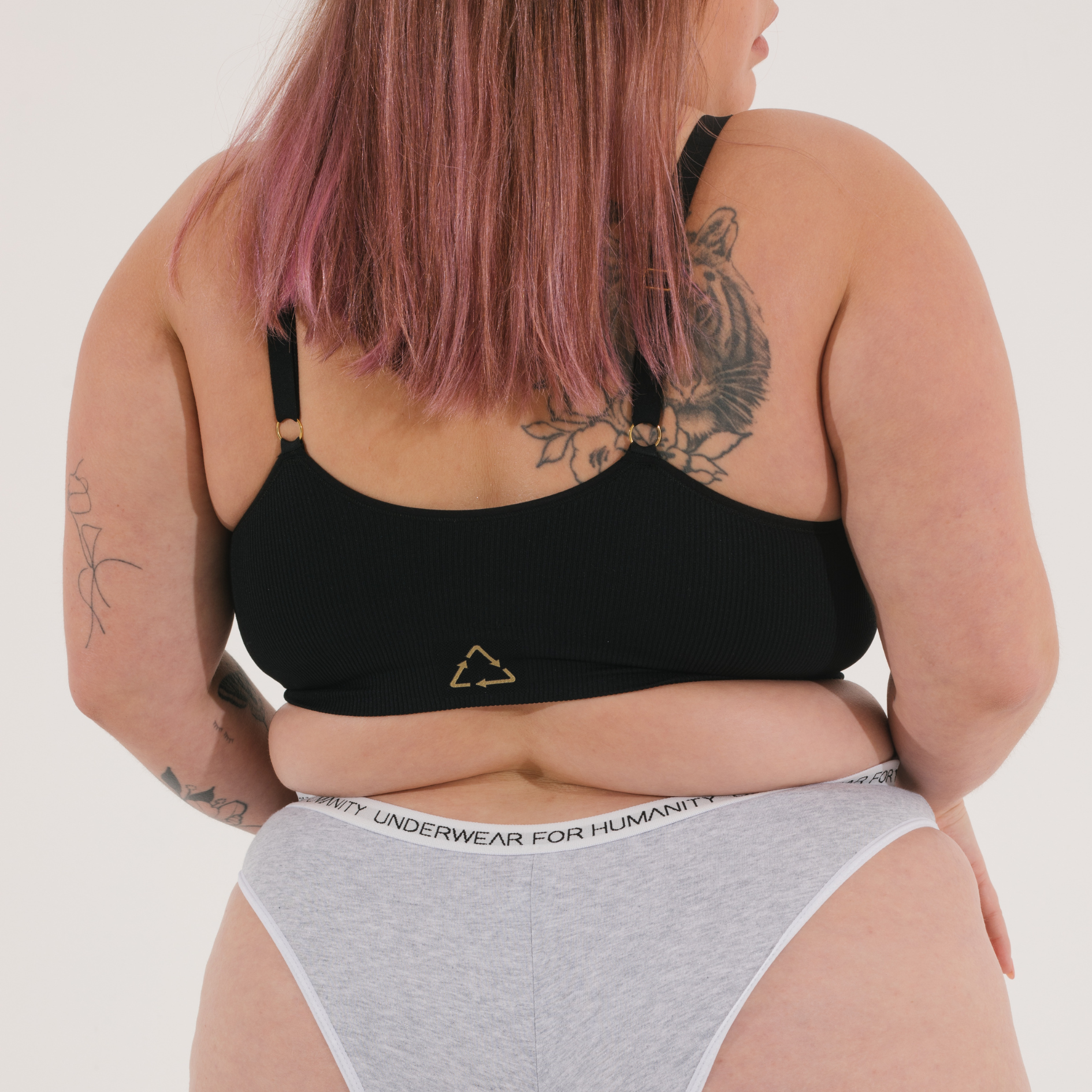 Sustainable, ethically produced black wireless bra by Underwear for Humanity. For DD-GG cup sizes. Recycled materials, flexible, supportive. Knitted bra and band, adjustable straps. Model wears the DD+ bra.