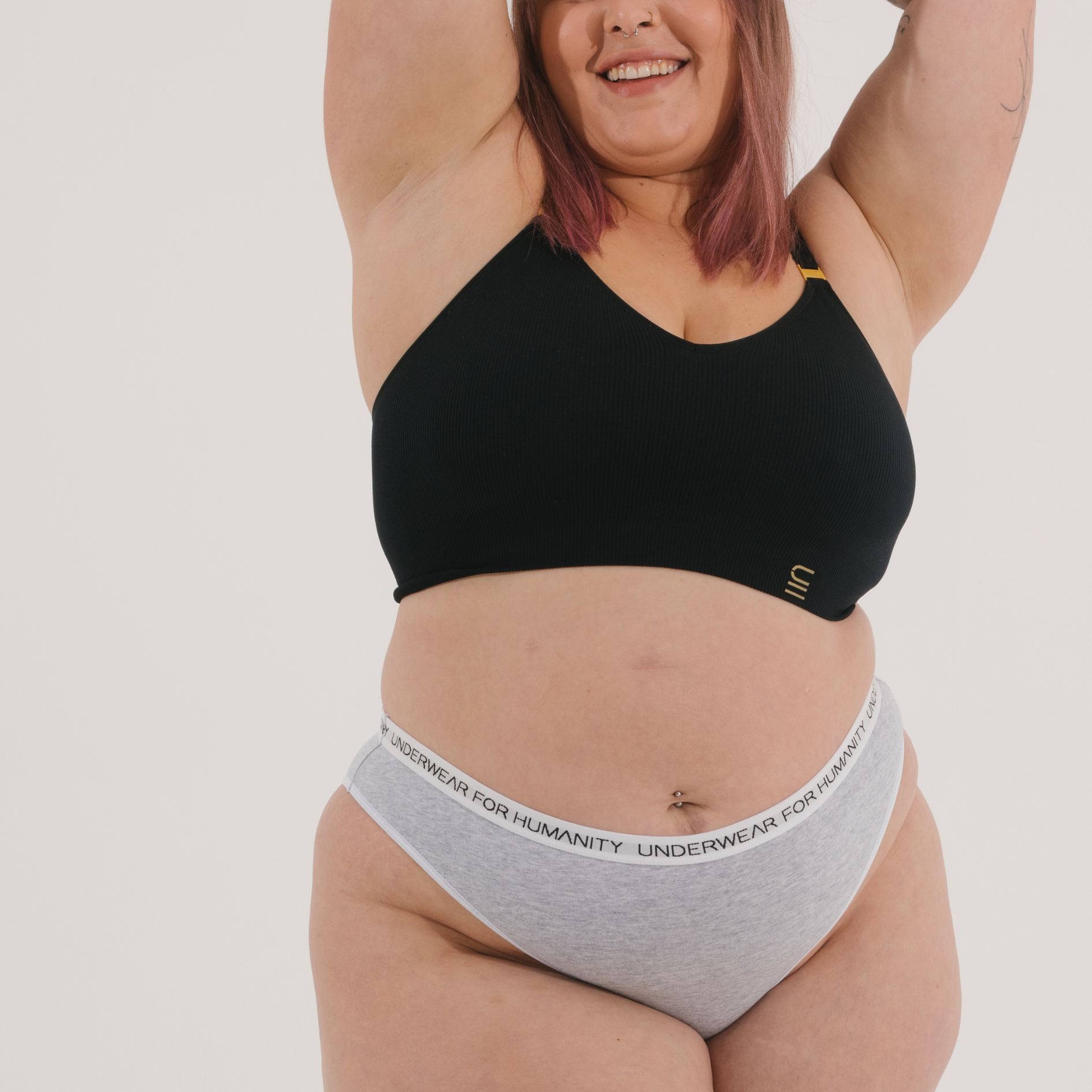 Sustainable, ethically produced black wireless bra by Underwear for Humanity. For DD-GG cup sizes. Recycled materials, flexible, supportive. Knitted bra and band, adjustable straps. Model wears the DD+ bra.