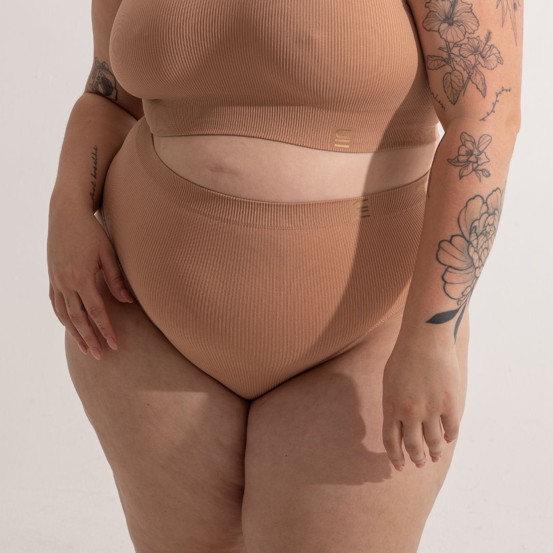 Sustainable, ethically made nude 3 - light beige skin tone, high waist seam free g-string by Underwear for Humanity: Flexible and comfortable, stretches across sizes. Models wear high-waisted G -string underwear. Underwear sits high on the waist, high on the seat, and smooth on the body, made from recycled nylon.