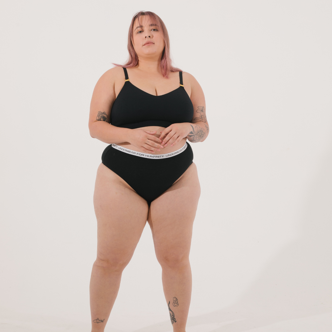 Underwear for Humanity, sustainable, organic and ethically made black cotton underwear. Soft , breathable, full coverage, sits high on waist. Model wears High waisted Cotton underwear in black with a white, recycled nylon elastic waist band.
