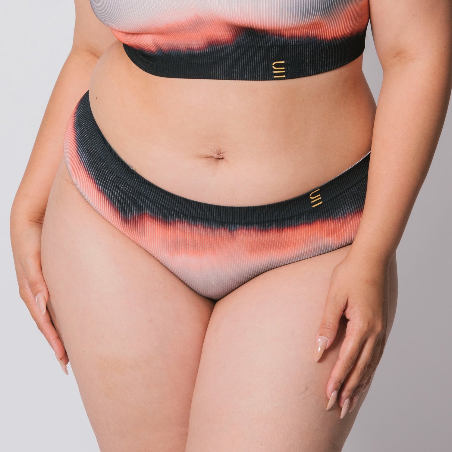 Underwear for Humanity, sustainable, organic and ethically made gradient underwear.  Soft , breathable, Cheeky coverage, sits high on hips. Model wears cheeky underwear in flame, recycled nylon elastic waist band.