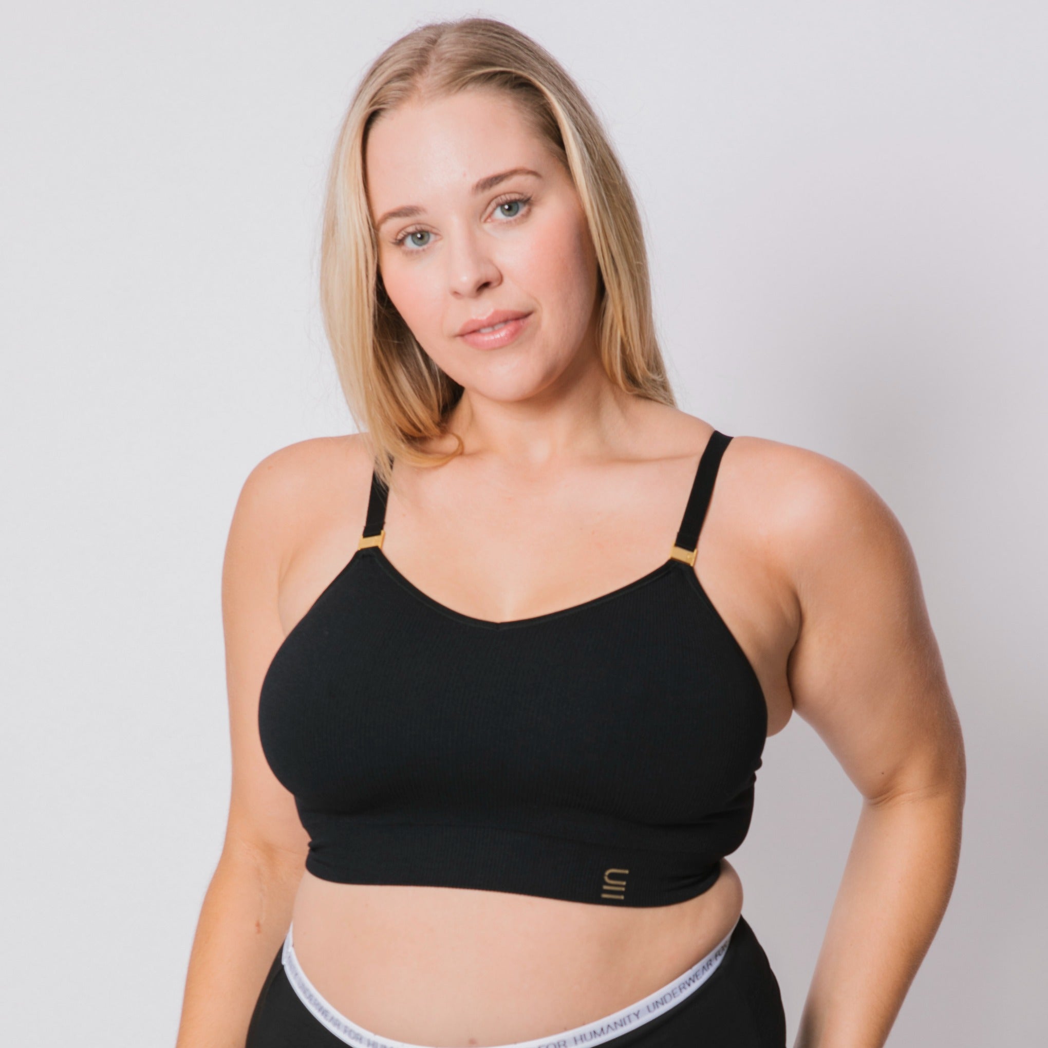 Sustainable, ethically produced black wireless bra by Underwear for Humanity. For DD-GG cup sizes. Recycled materials, flexible, supportive. Knitted bra and band, adjustable straps. Model wears the DD+ bra.