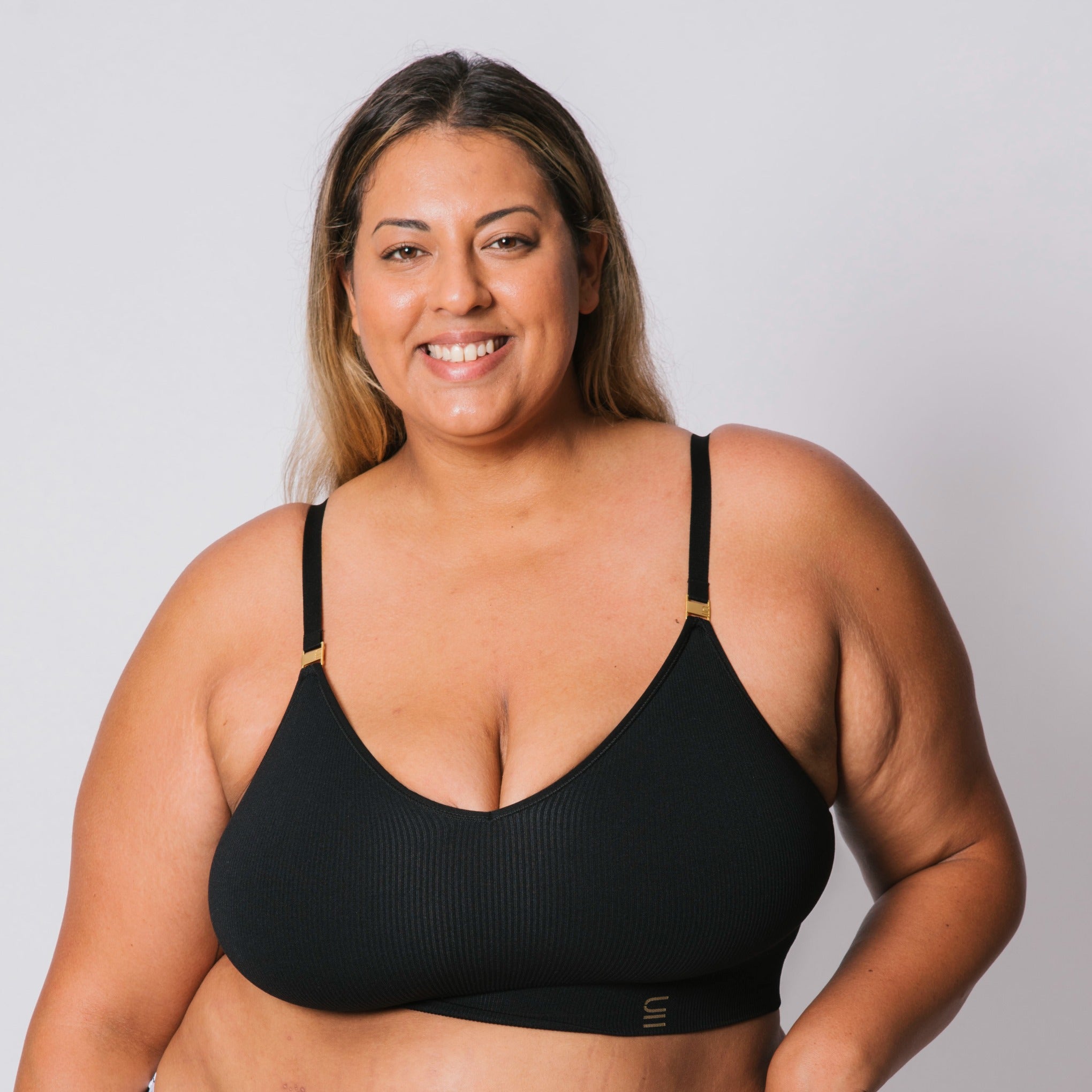 Sustainable, ethically produced black wireless bra by Underwear for Humanity. For DD-GG cup sizes. Recycled materials, flexible, supportive. Knitted bra and band, adjustable straps. Model wears the DD+ bra.