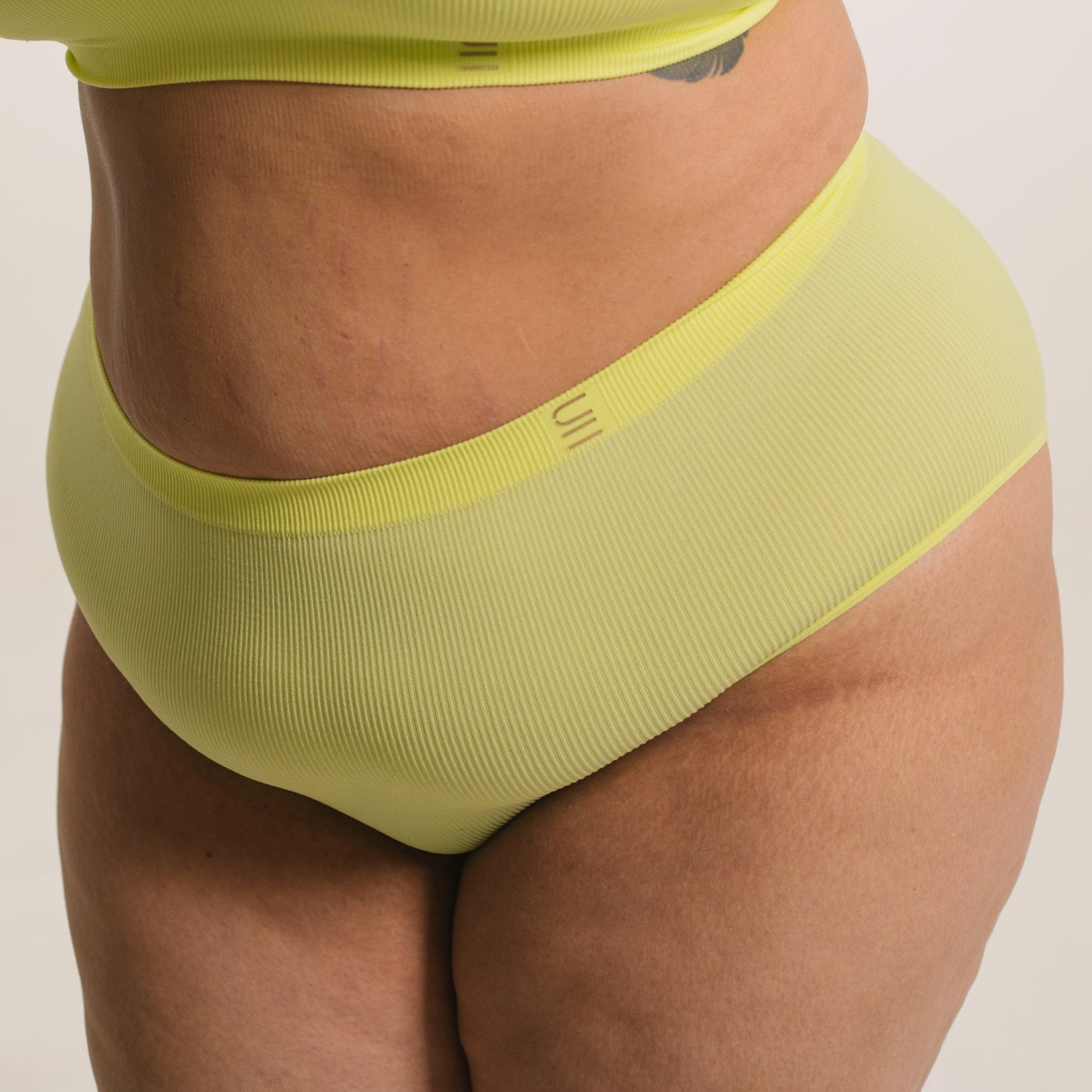 Sustainable, ethically made lime high waist seam free brief by Underwear for Humanity: Flexible and comfortable, stretches across sizes. Models wear high waisted ethical underwear. Underwear is made from recycled nylon and sits high on the waist, full seat coverage and smooth on the body.