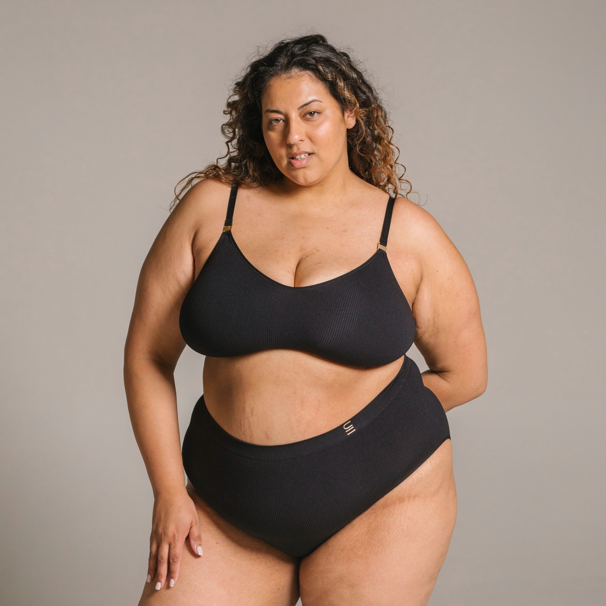 Sustainable, ethically produced black wireless bra by Underwear for Humanity. For DD-GG cup sizes. Recycled materials, flexible, supportive. Knitted bra and band, adjustable straps. Model wears the DD+ bra.