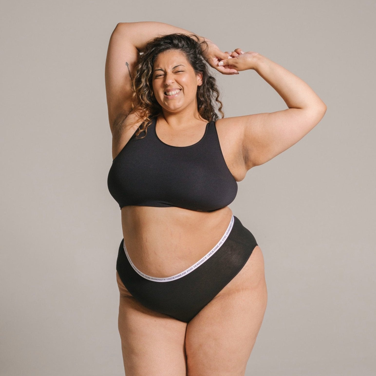 Underwear for Humanity, sustainable, organic and ethically made black cotton underwear. Soft , breathable, full coverage, sits high on waist. Model wears High waisted Cotton underwear in black with a white, recycled nylon elastic waist band.
