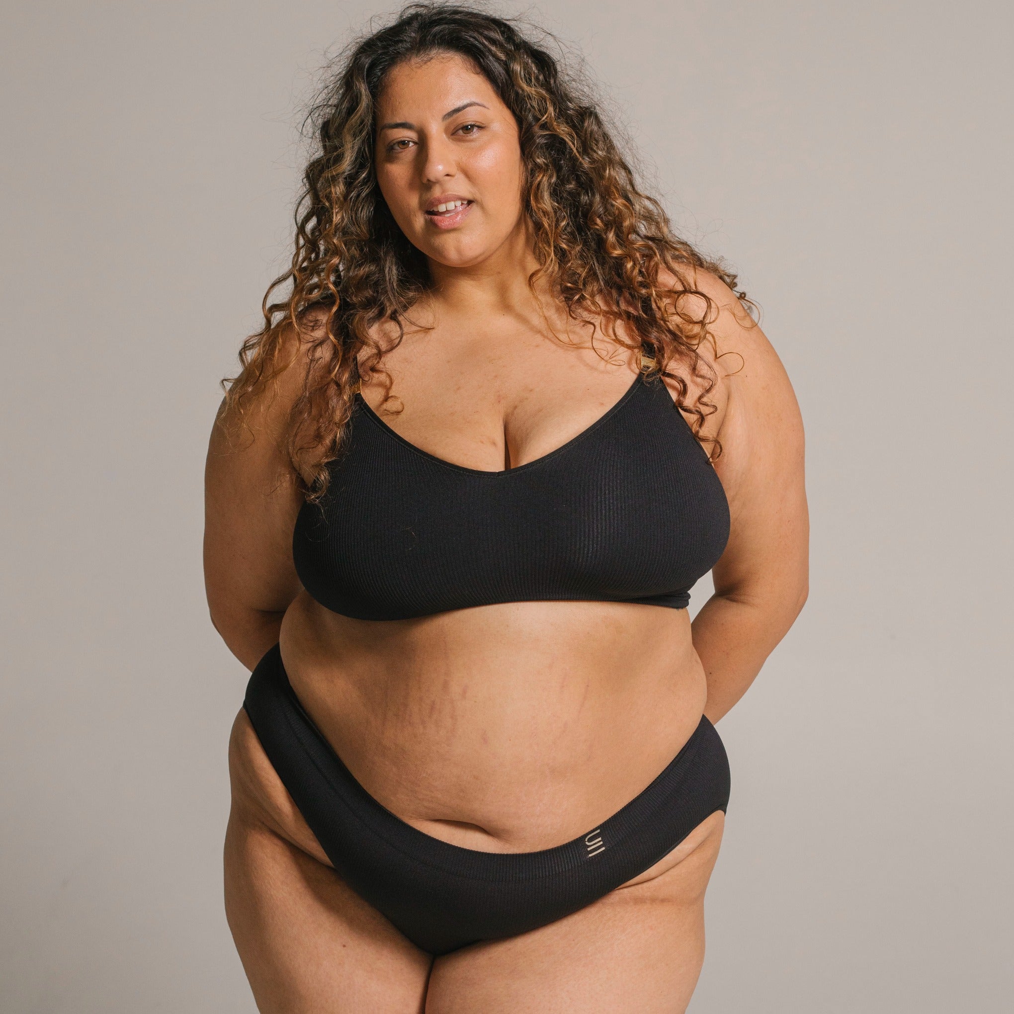 Ethically made recycled seam free black bikini brief by Underwear for Humanity: Flexible and comfortable, stretches across sizes. Models wear bikini brief underwear. Underwear is made from recycled nylon and sits low on the waist, full seat coverage and smooth on the body.