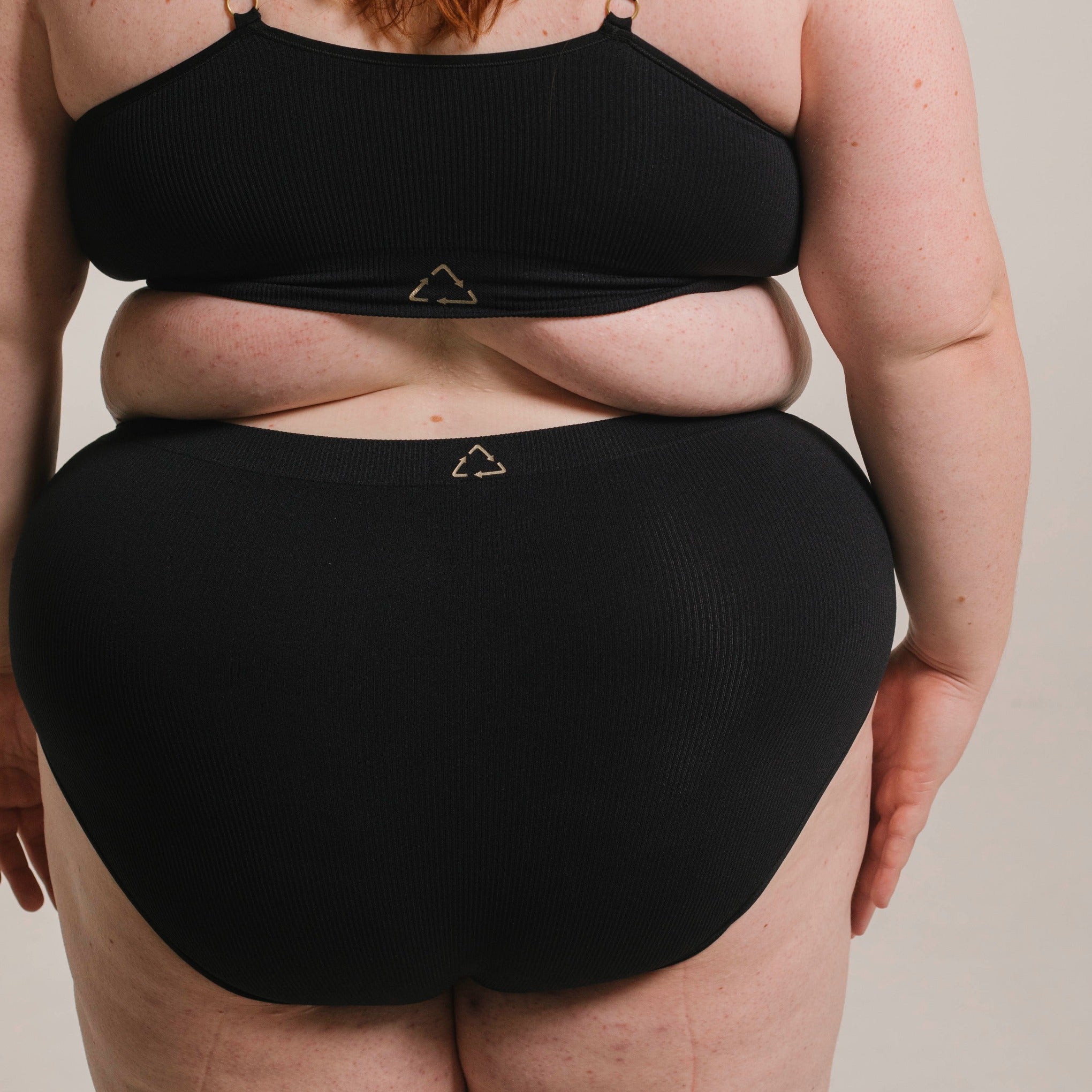 Sustainable, ethically produced black wireless bra by Underwear for Humanity. For H+ cup sizes. Recycled materials, flexible, supportive. Knitted bra and band, adjustable straps. Model wears the H+ bra.