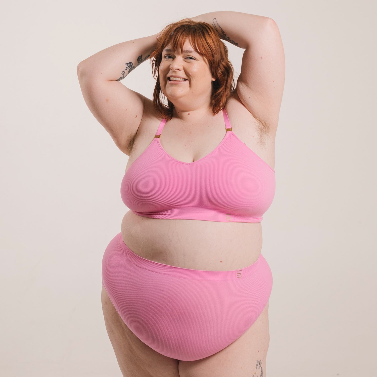 Sustainable, ethically produced pink wireless bra by Underwear for Humanity. For DD-GG cup sizes. Recycled materials, flexible, supportive. Knitted bra and band, adjustable straps. Model wears the DD+ bra.