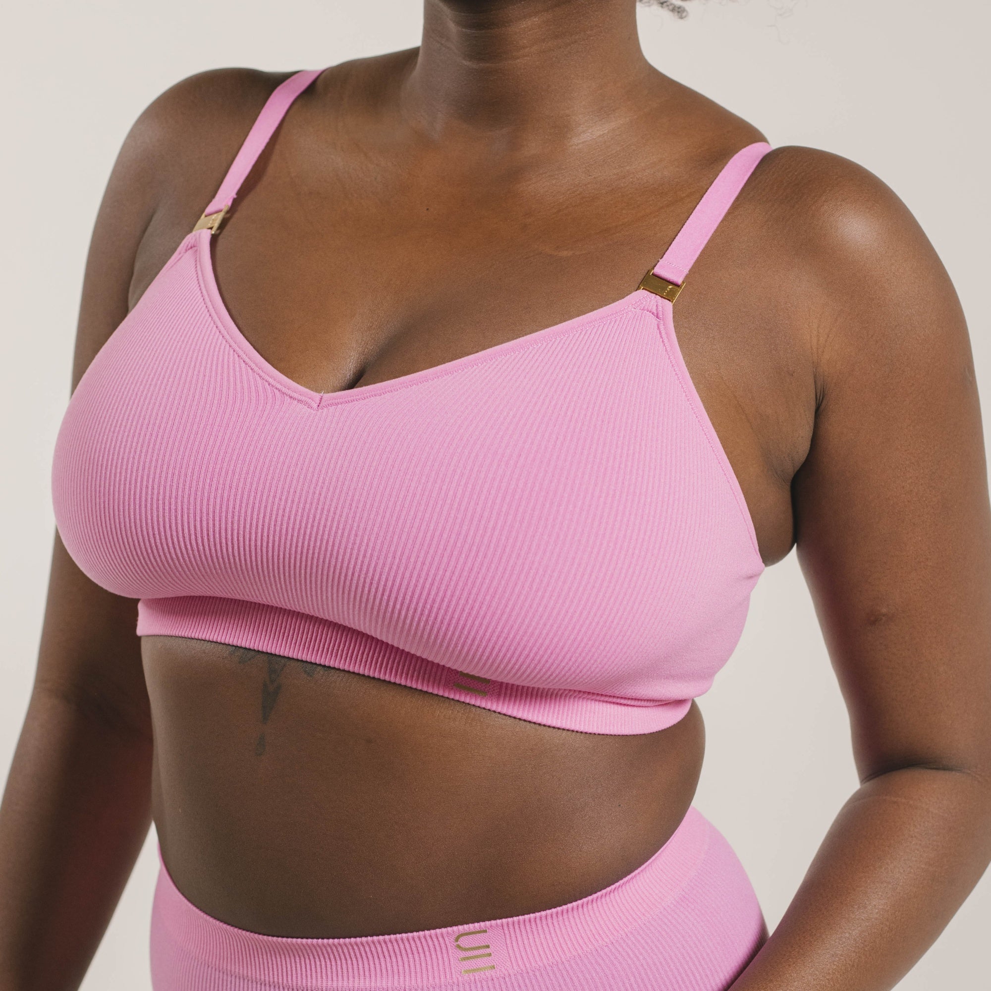 Sustainable, ethically produced pink wireless bra by Underwear for Humanity. For DD-GG cup sizes. Recycled materials, flexible, supportive. Knitted bra and band, adjustable straps. Model wears the DD+ bra.