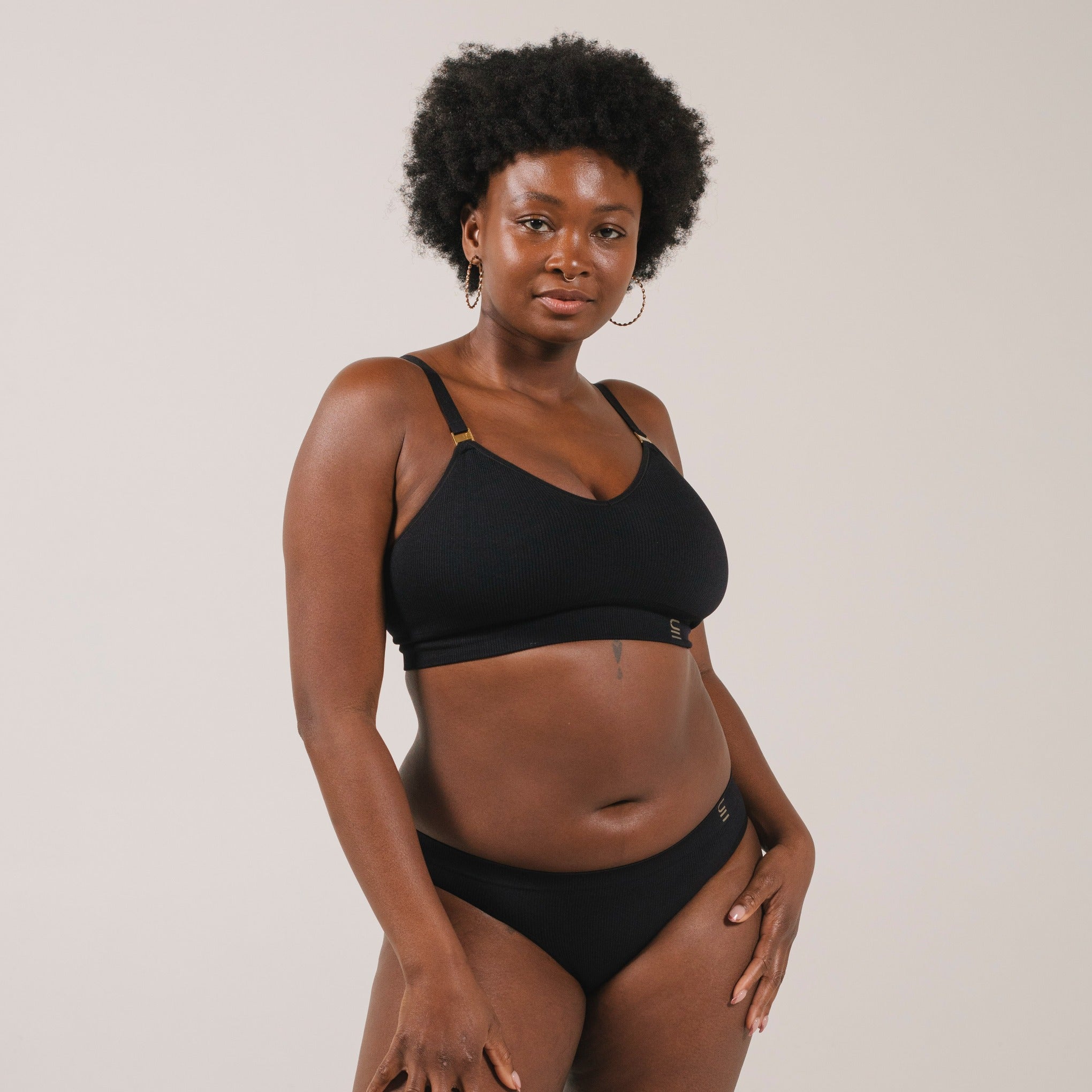 Ethically made recycled seam free black bikini brief by Underwear for Humanity: Flexible and comfortable, stretches across sizes. Models wear bikini brief underwear. Underwear is made from recycled nylon and sits low on the waist, full seat coverage and smooth on the body.