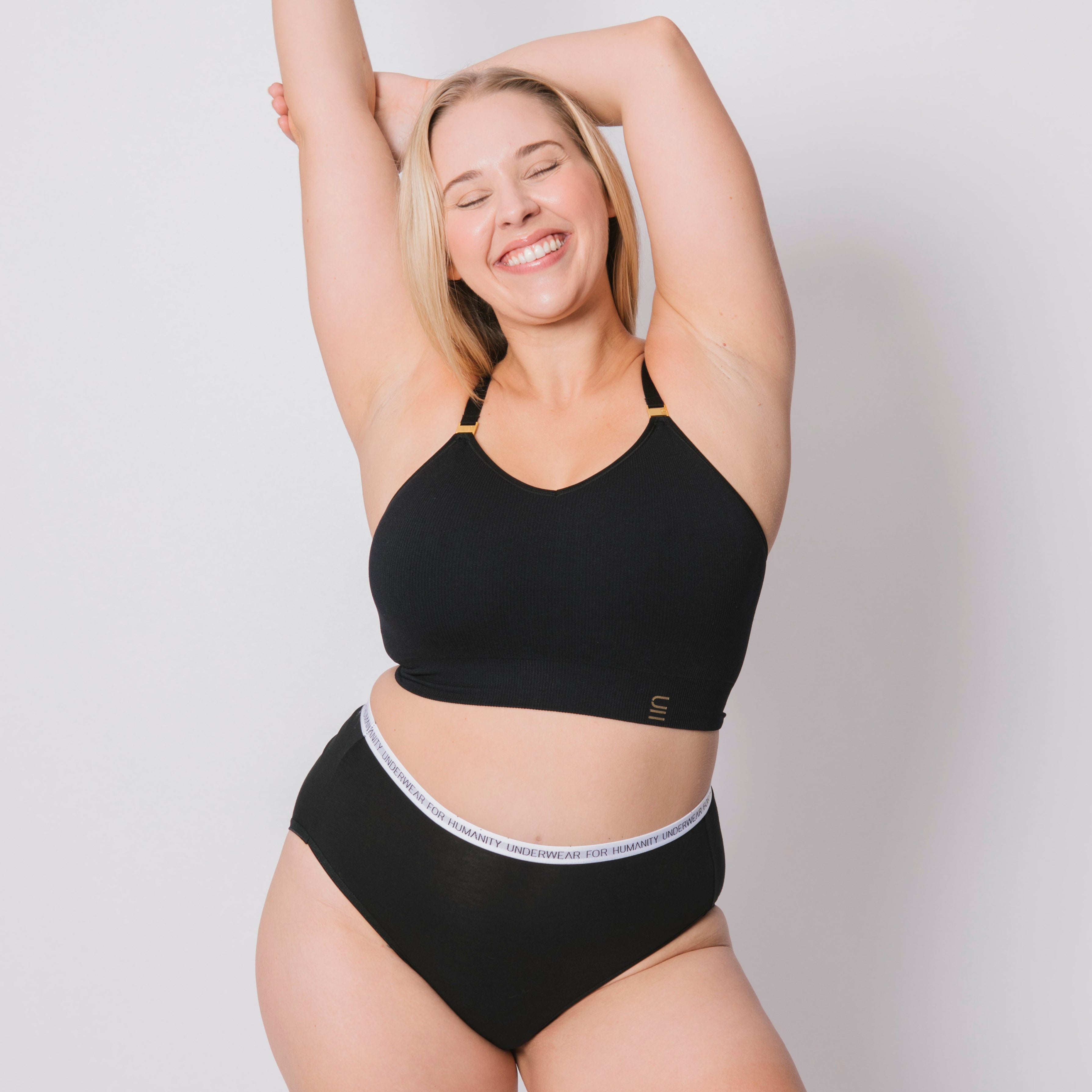 Underwear for Humanity, sustainable, organic and ethically made black cotton underwear. Soft , breathable, full coverage, sits high on waist. Model wears High waisted Cotton underwear in black with a white, recycled nylon elastic waist band.