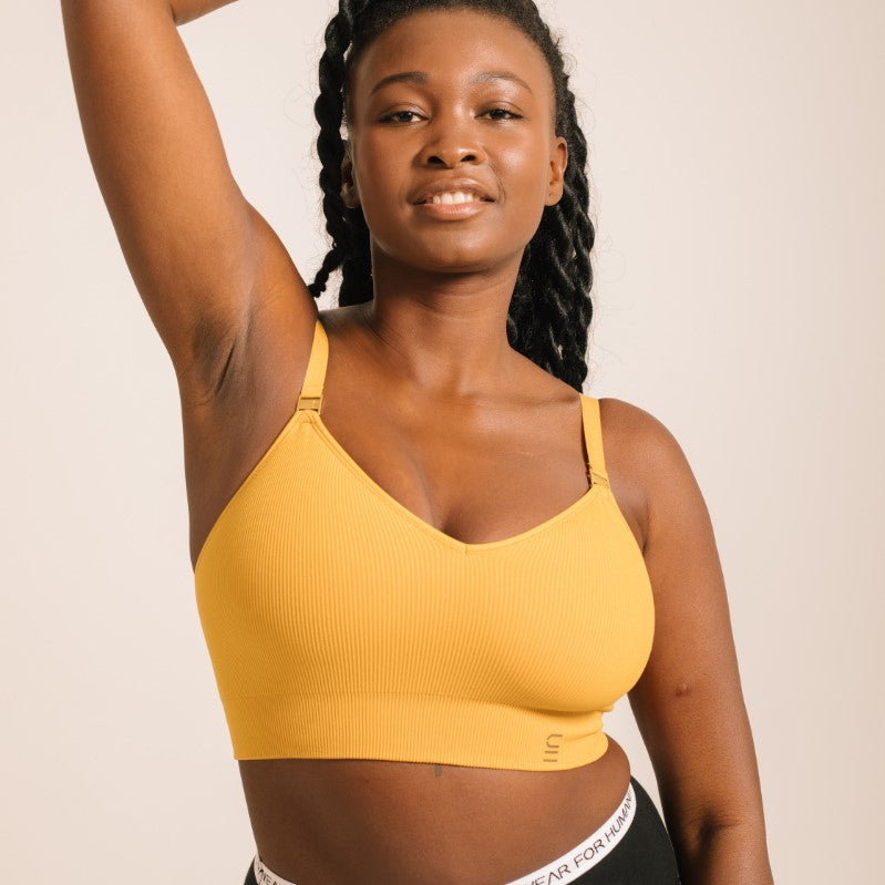 Sustainable, ethically produced gold wireless bra by Underwear for Humanity. For DD-GG cup sizes. Recycled materials, flexible, supportive. Knitted bra and band, adjustable straps. Model wears the DD+ bra.