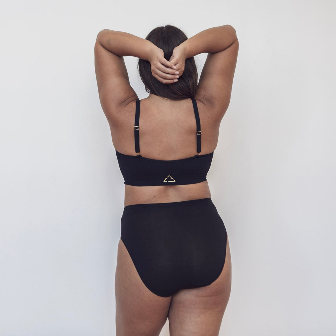 Sustainable Black wireless bra by Underwear For Humanity: ethical, sustainable. A -D cup sizes. Recycled materials, flexible, supportive. Knitted bra and band, adjustable straps. Model wears A-D bra