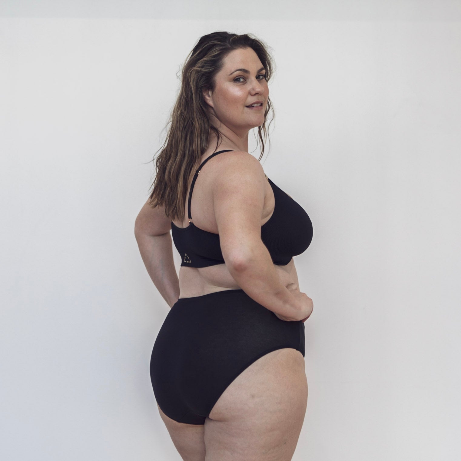Sustainable, ethically produced black wireless bra by Underwear for Humanity. For DD-GG cup sizes. Recycled materials, flexible, supportive. Knitted bra and band, adjustable straps. Model wears the DD+ bra.