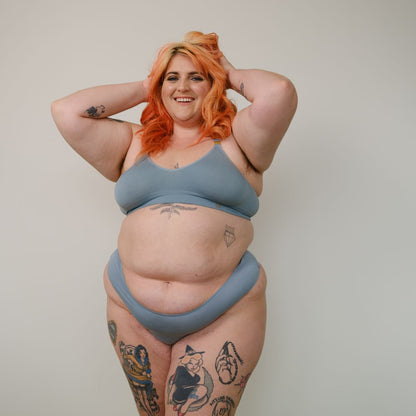 Sustainable mineral blue high waist g-string by Underwear for Humanity: ethical, sustainable. sizes 6-26. Models wear high-waisted G -string underwear. underwear sits high on the waist, sits smooth on the body, made from Tencel and recycled materials.