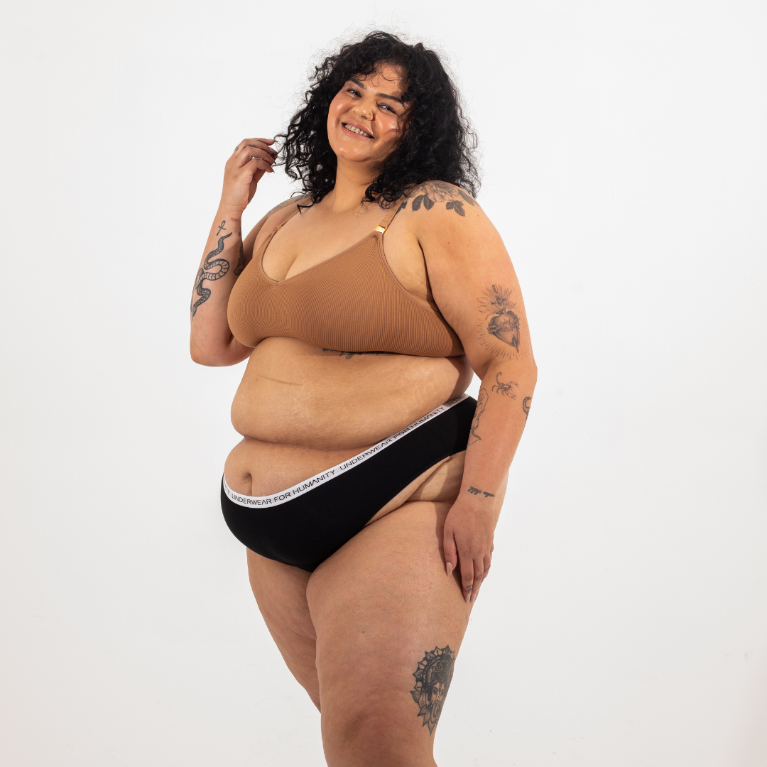 Underwear for Humanity, sustainable, organic and ethically made black cotton underwear.  Soft , breathable, Cheeky coverage, sits high on hips. Model wears Cheeky Cotton underwear in black with a white, recycled nylon elastic waist band.  
