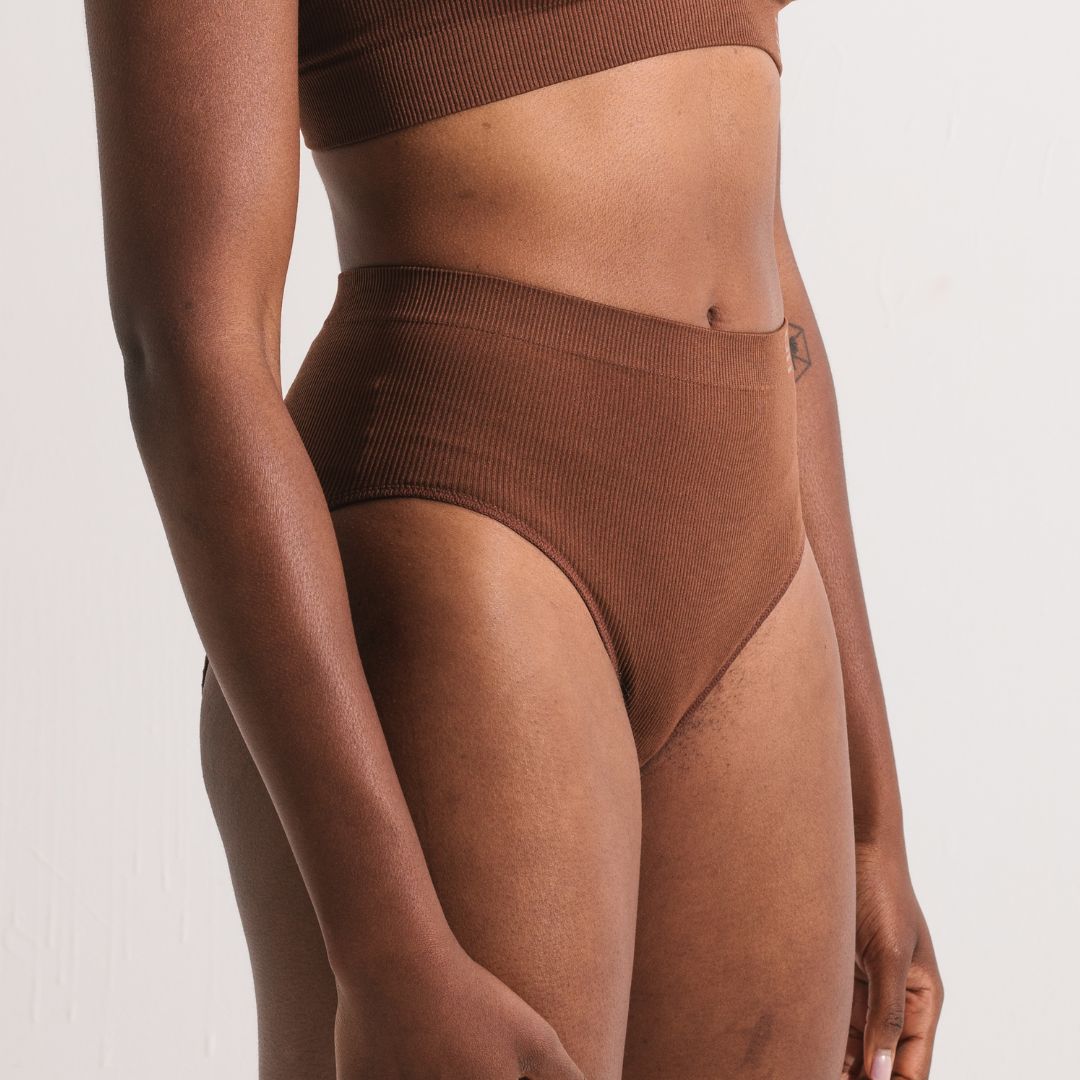 Sustainable nude 5 medium dark skin tone seam free high waist brief by Underwear for Humanity: ethical, sustainable. sizes 6-26. light, breathable, stretches across sizes. Models wear high-waisted underwear. underwear sits high on the waist, full seat coverage, Seam free underwear. made from recycled nylon