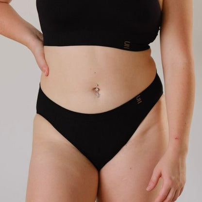 Ethically made recycled seam free black bikini brief by Underwear for Humanity: Flexible and comfortable, stretches across sizes. Models wear bikini brief underwear. Underwear is made from recycled nylon and sits low on the waist, full seat coverage and smooth on the body.
