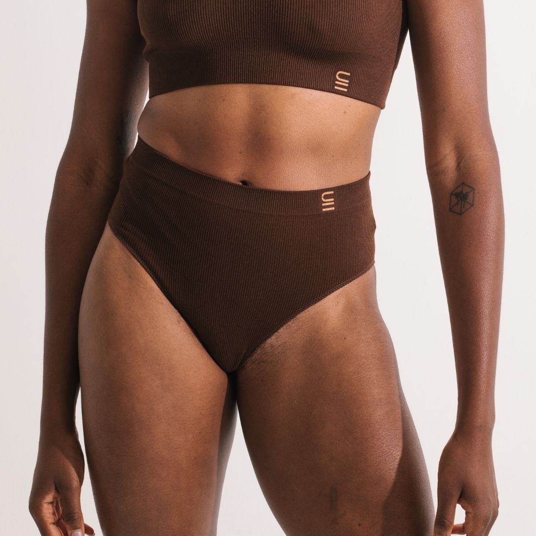 Sustainable, ethically made Nude 6 - Dark Skin Tone high waist seam free g-string by Underwear for Humanity: Flexible and comfortable, stretches across sizes. Models wear high-waisted G -string underwear. Underwear sits high on the waist, high on the seat, and smooth on the body, made from recycled nylon. 