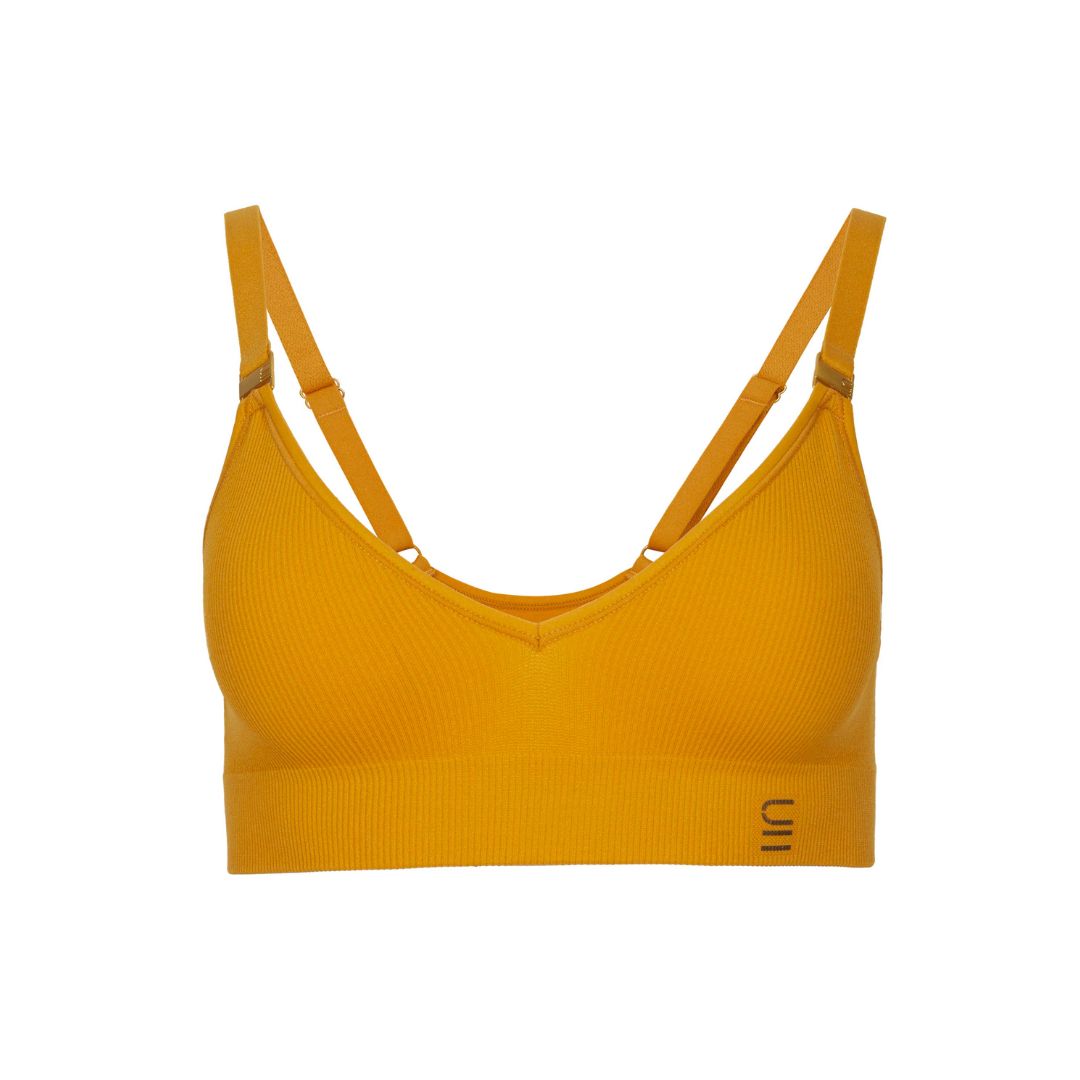 Sustainable, ethically produced gold wireless bra by Underwear for Humanity. For DD-GG cup sizes. Recycled materials, flexible, supportive. Knitted bra and band, adjustable straps. Model wears the DD+ bra.