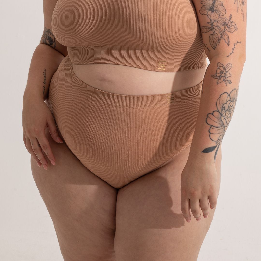 Sustainable, ethically made nude 3 - light beige skin tone, high waist seam free g-string by Underwear for Humanity: Flexible and comfortable, stretches across sizes. Models wear high-waisted G -string underwear. Underwear sits high on the waist, high on the seat, and smooth on the body, made from recycled nylon. 
