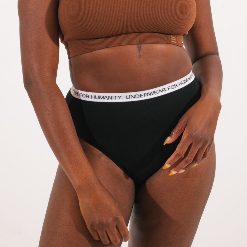 Underwear for Humanity, sustainable, organic and ethically made black cotton underwear.  Soft , breathable, full coverage, sits high on waist. Model wears High waisted Cotton underwear in black with a white, recycled nylon elastic waist band.  