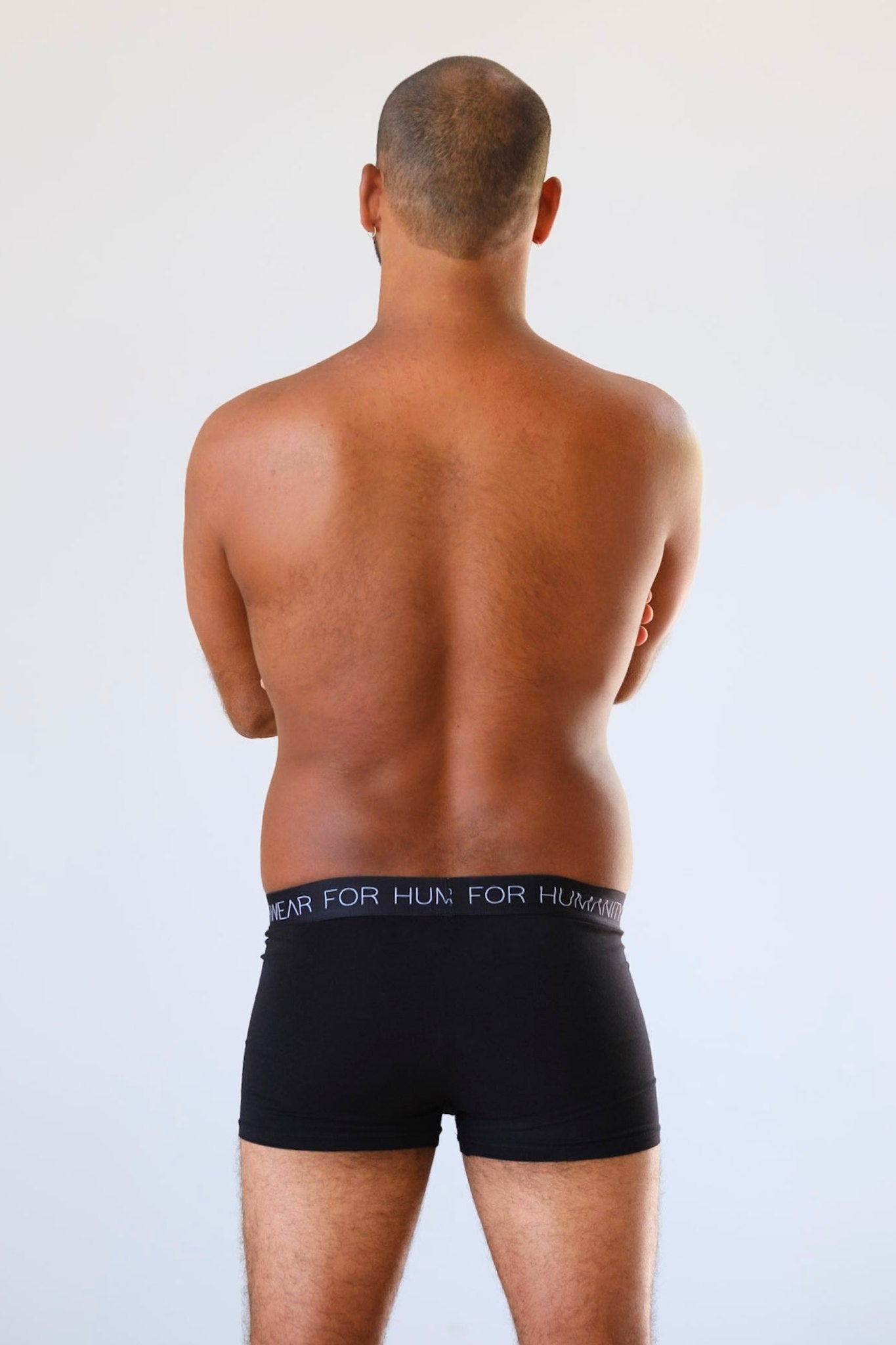 Sustainable, ethically made black trunk style underwear. Long leg, wide thigh fit with elastic bind, no riding, cup support close to the body. made with organic fabric and recycled elastic, thin, no dig waist band. Model wears shorts