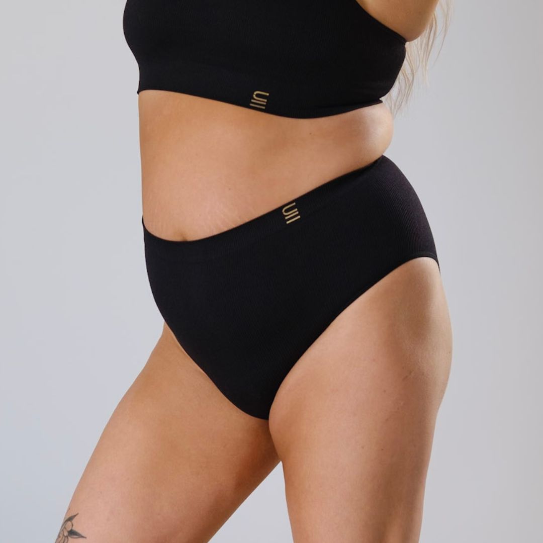 Sustainable, ethically made Black high waist seam free brief by Underwear for Humanity: Flexible and comfortable, stretches across sizes. Models wear high waisted ethical underwear. Underwear is made from recycled nylon and sits high on the waist, full seat coverage and smooth on the body.