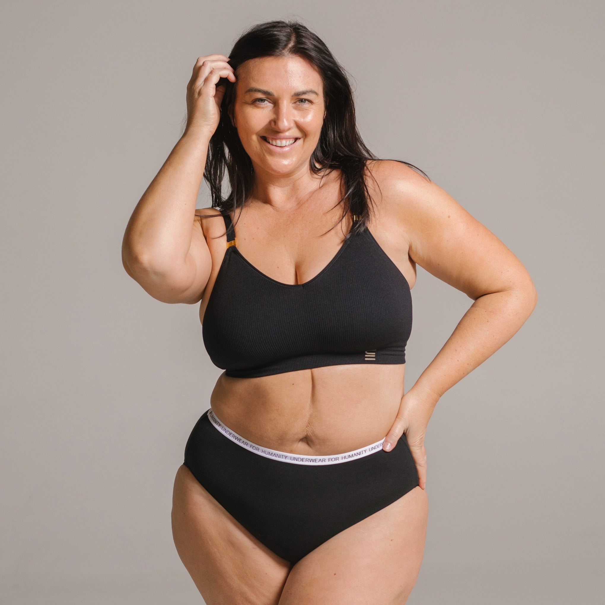 Underwear for Humanity, sustainable, organic and ethically made black cotton underwear.  Soft , breathable, full coverage, sits high on waist. Model wears High waisted Cotton underwear in black with a white, recycled nylon elastic waist band.  