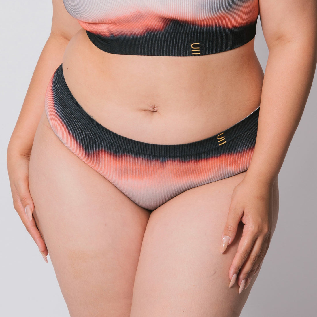 Underwear for Humanity, sustainable, organic and ethically made gradient underwear.  Soft , breathable, Cheeky coverage, sits high on hips. Model wears cheeky underwear in flame, recycled nylon elastic waist band.