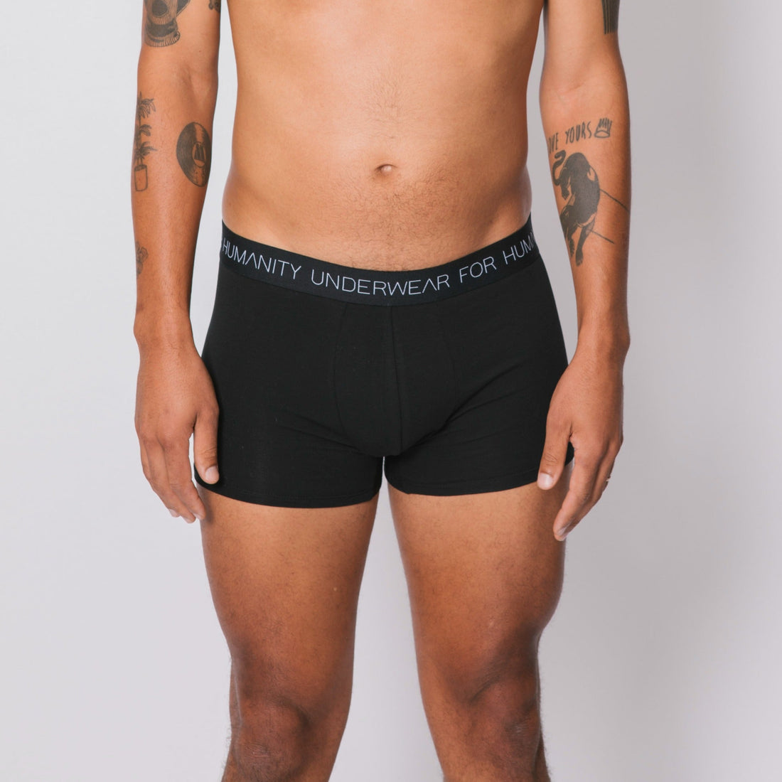 Sustainable, ethically made black trunk style underwear. Long leg, wide thigh fit with elastic bind, no riding, cup support close to the body. made with organic fabric and recycled elastic, thin, no dig waist band. Model wears shorts