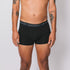 Sustainable, ethically made black trunk style underwear. Long leg, wide thigh fit with elastic bind, no riding, cup support close to the body. made with organic fabric and recycled elastic, thin, no dig waist band. Model wears shorts