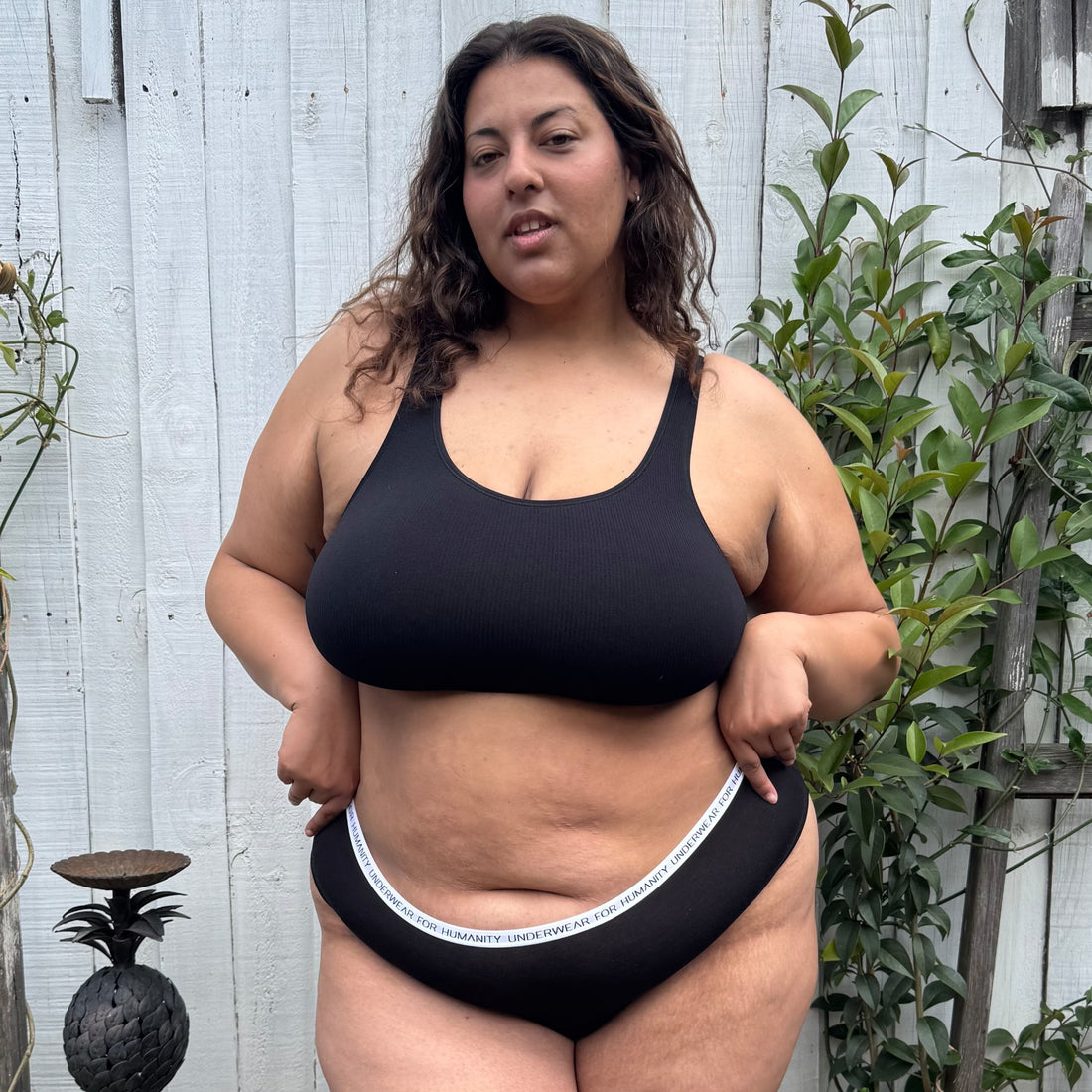 Underwear for Humanity, sustainable, organic and ethically made black cotton underwear.  Soft , breathable, Cheeky coverage, sits high on hips. Model wears Cheeky Cotton underwear in black with a white, recycled nylon elastic waist band.  