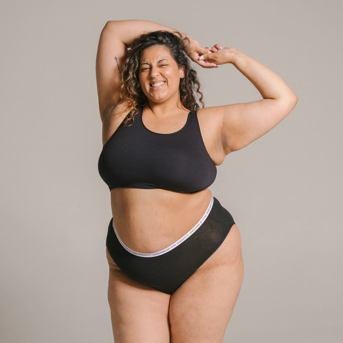 Underwear for Humanity, sustainable, organic and ethically made black cotton underwear.  Soft , breathable, full coverage, sits high on waist. Model wears High waisted Cotton underwear in black with a white, recycled nylon elastic waist band.