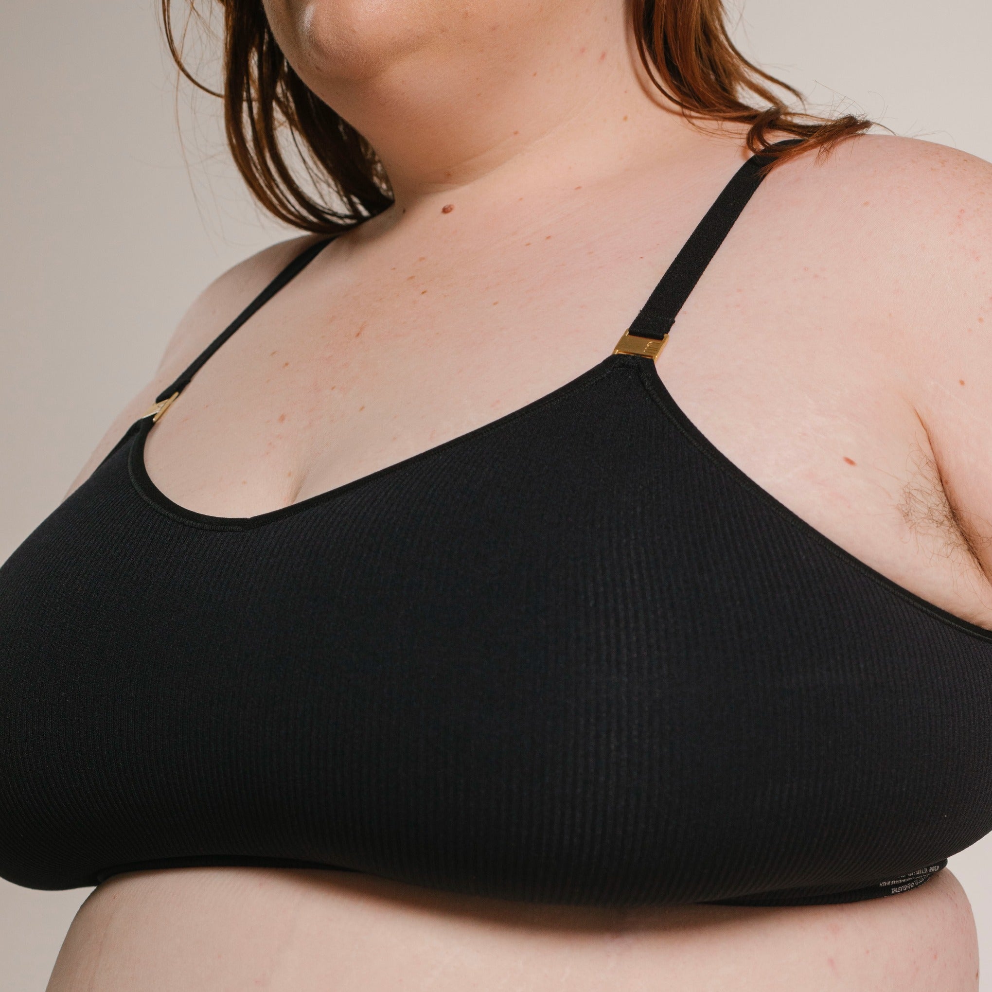 Sustainable, ethically produced black wireless bra by Underwear for Humanity. For H+ cup sizes. Recycled materials, flexible, supportive. Knitted bra and band, adjustable straps. Model wears the H+ bra.