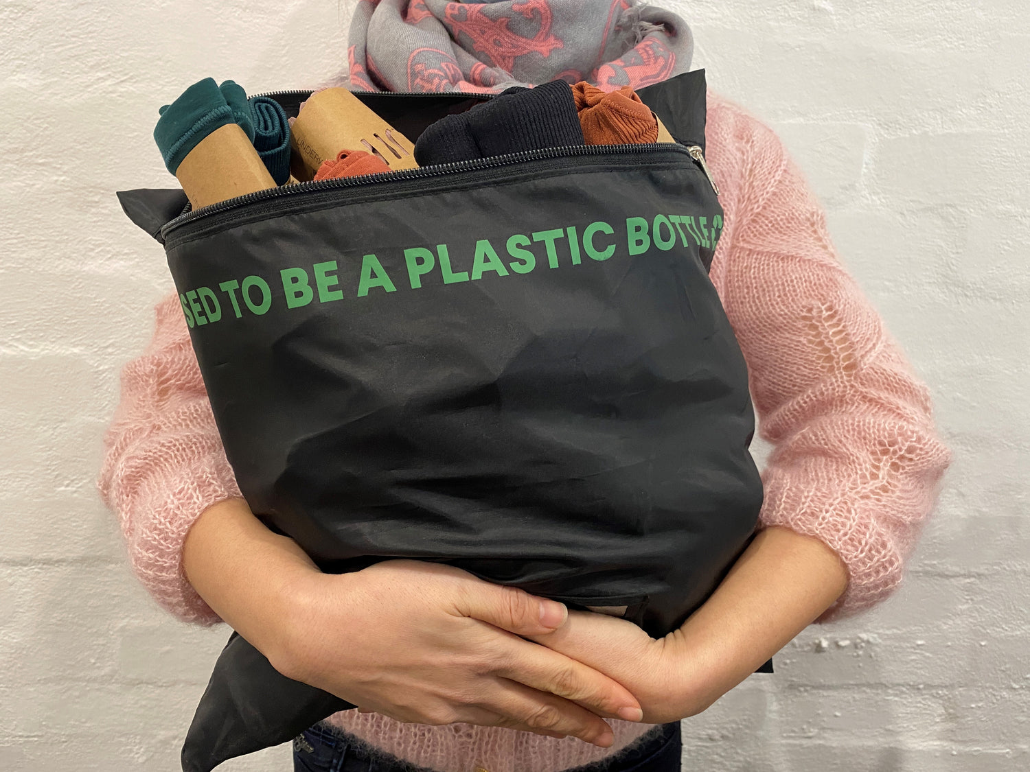 Woman holding a reusable bag with the message I Used To Be A Plastic Bottle on its side