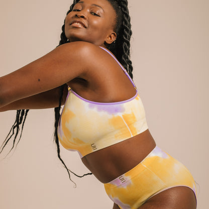 Sustainable sunrise yellow and purple tie dye seam free high waist brief by Underwear for Humanity: ethical, sustainable. sizes 6-26. light, breathable, stretches across sizes. Models wear high-waisted underwear. underwear sits high on the waist, full seat coverage, Seam free underwear. made from recycled nylon