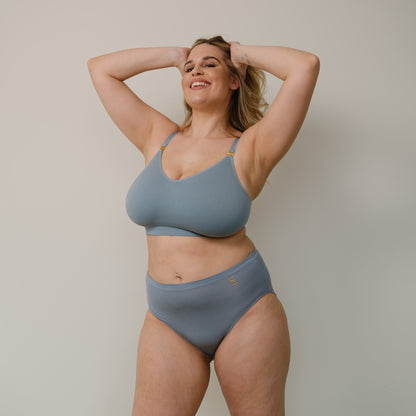 Sustainable, ethically produced mineral blue wireless bra by Underwear for Humanity. For DD-GG cup sizes. Recycled materials, flexible, supportive. Knitted bra and band, adjustable straps. Model wears the DD+ bra.