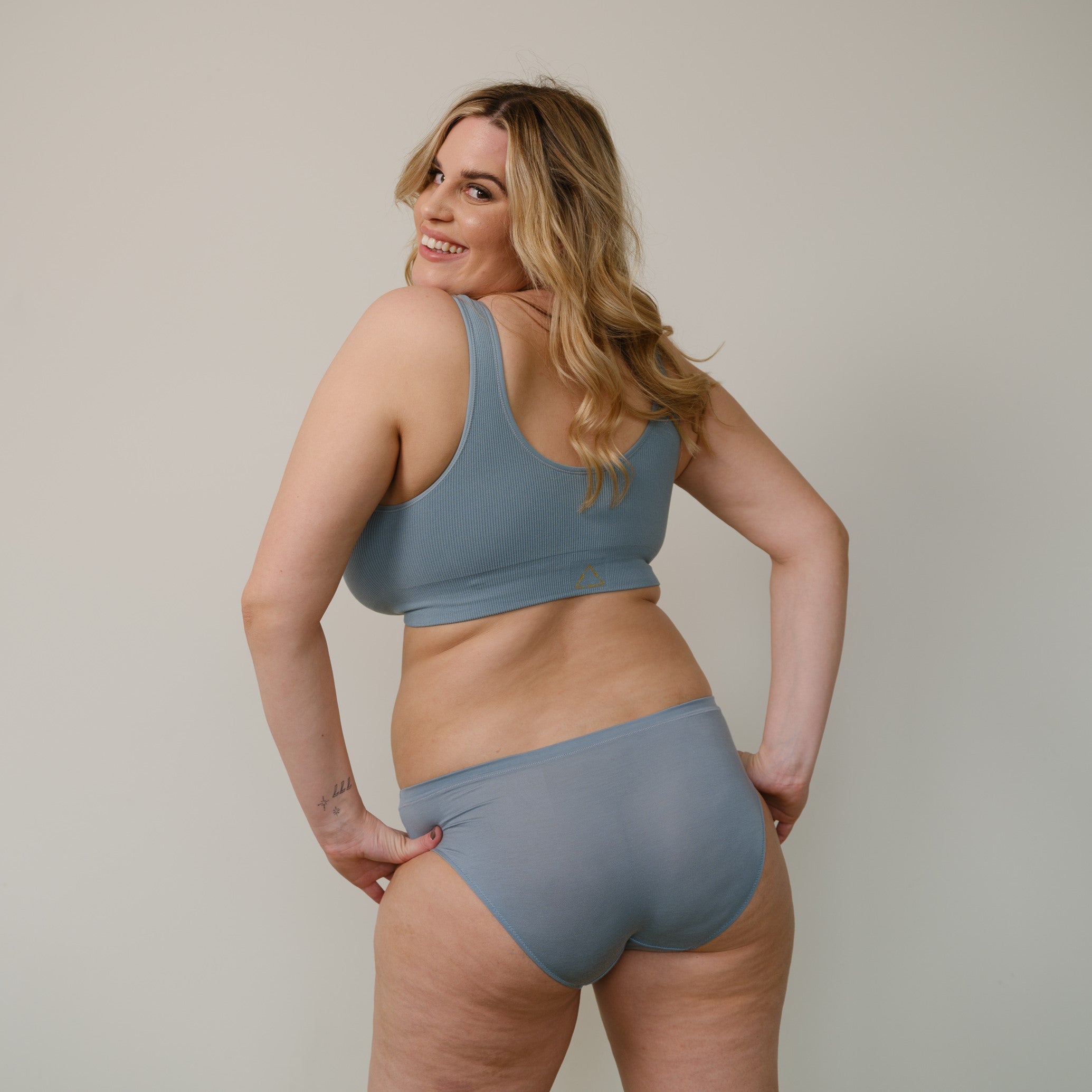 Sustainable, ethically produced mineral blue bra crop by Underwear for Humanity: stronger support for larger bust, D - GG cup sizes. Recycled materials, knitted bra and band, seamfree, made from recycled nylon. Model wears the D+ Crop