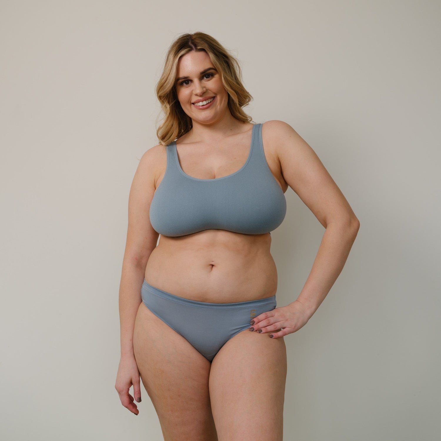 Sustainable, ethically produced mineral blue bra crop by Underwear for Humanity: stronger support for larger bust, D - GG cup sizes. Recycled materials, knitted bra and band, seamfree, made from recycled nylon. Model wears the D+ Crop