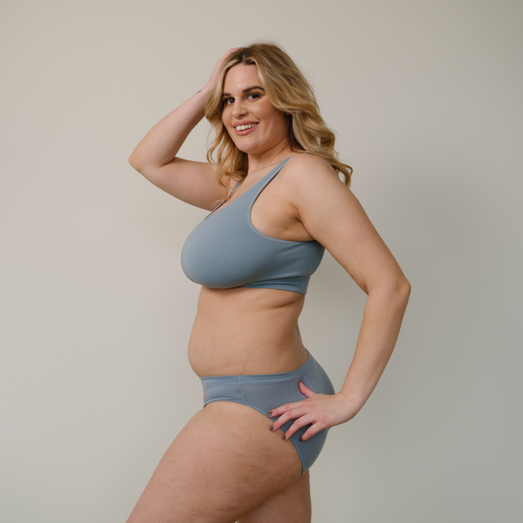 Sustainable, ethically produced mineral blue bra crop by Underwear for Humanity: stronger support for larger bust, D - GG cup sizes. Recycled materials, knitted bra and band, seamfree, made from recycled nylon. Model wears the D+ Crop