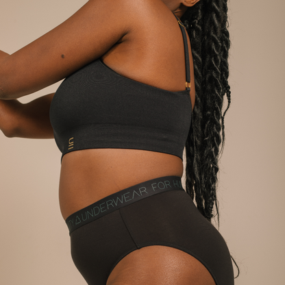 Sustainable black high waist brief by Underwear for Humanity: ethical, sustainable. sizes 6-30 light, breathable. Models wear high-waisted underwear. underwear sits high on the waist, full seat coverage. smooth under clothing. made from Tencel and recycled materials, attached no-dig recycled elastic waist band.