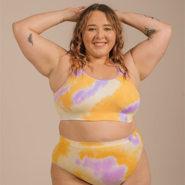 Sustainable, ethically produced sunrise- yellow orange and purple tie dye bra crop by Underwear for Humanity: stronger support for larger bust, D - GG cup sizes. Recycled materials, knitted bra and band, seamfree, made from recycled nylon. Models wear the D+ Crop